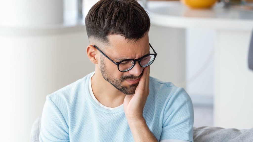 man holding face from toothache needs to see emergency dentist