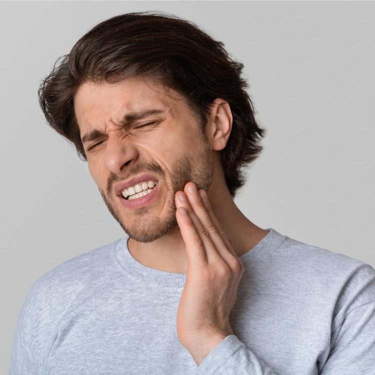 man holding his face in pain with toothache