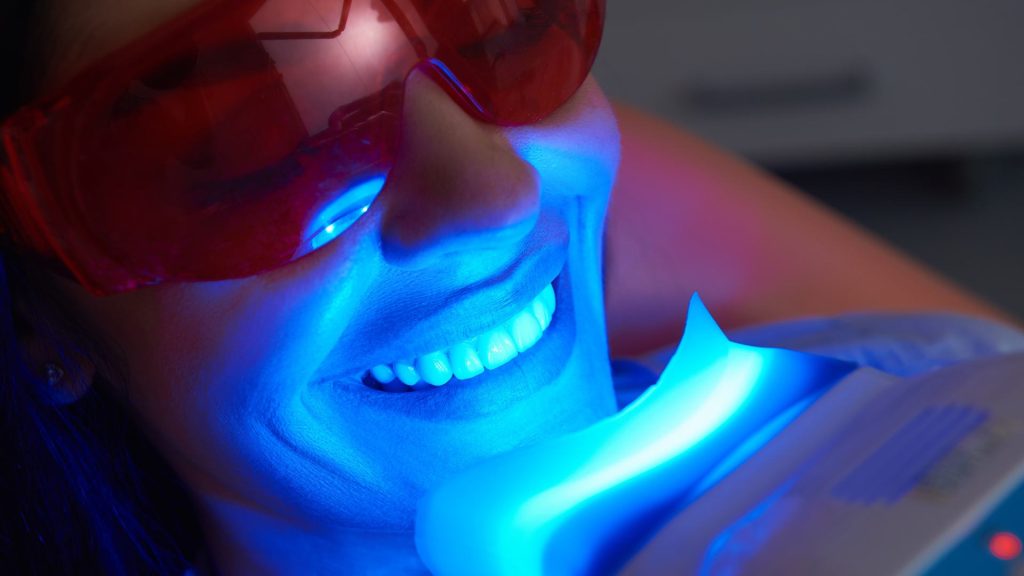 woman smiling while getting her teeth whitened