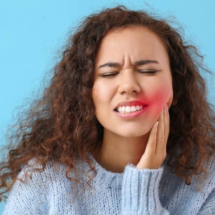 woman holding her face as her tooth is in pain