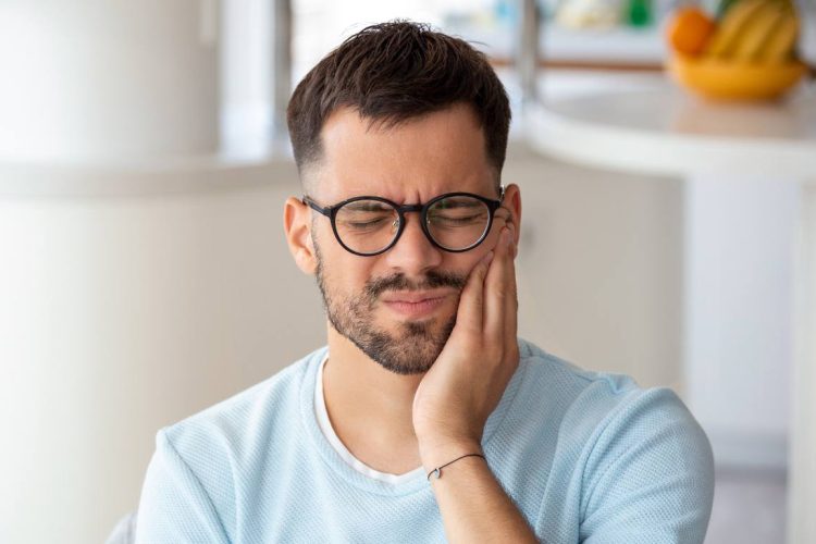 man holding his face in pain with toothache